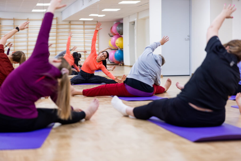 Ihmisiä liikuntatunnilla venyttelemässä.